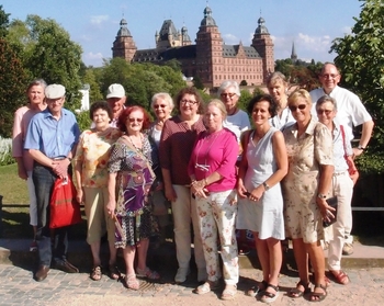 Der Ökumenische Besuchsdienstkreis im mediterranen Garten des Pompejanums mit dem Aschaffenburger Schloss Johannisburg